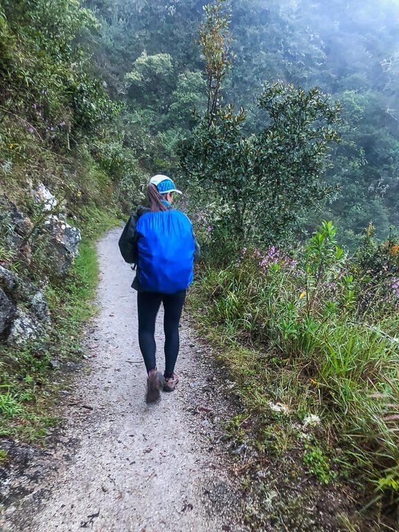 Kristen wearing backpack and cover walking on trail in Peru