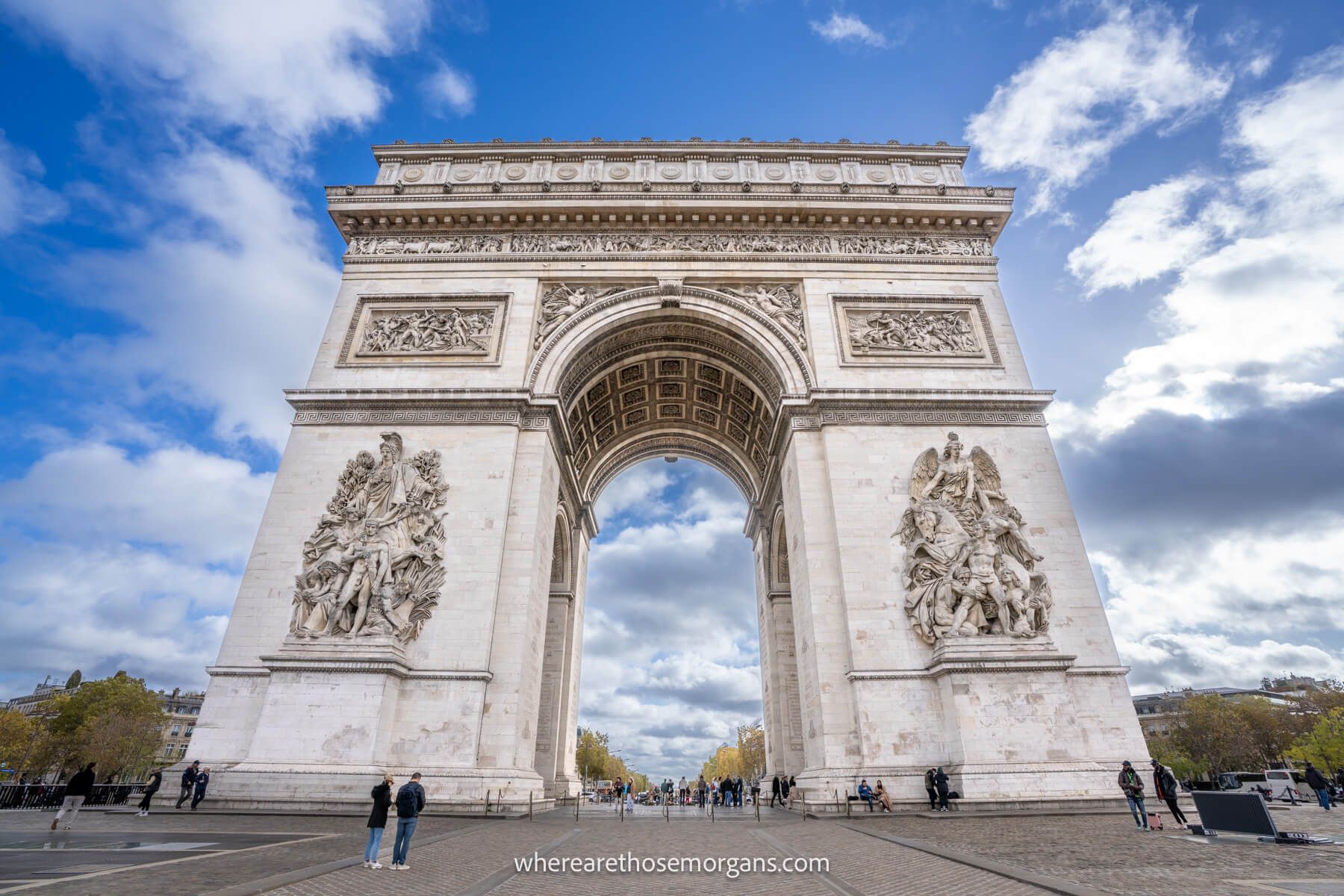 Photo of the Arc de Triomphe looking up from below against a blue sky with light clouds