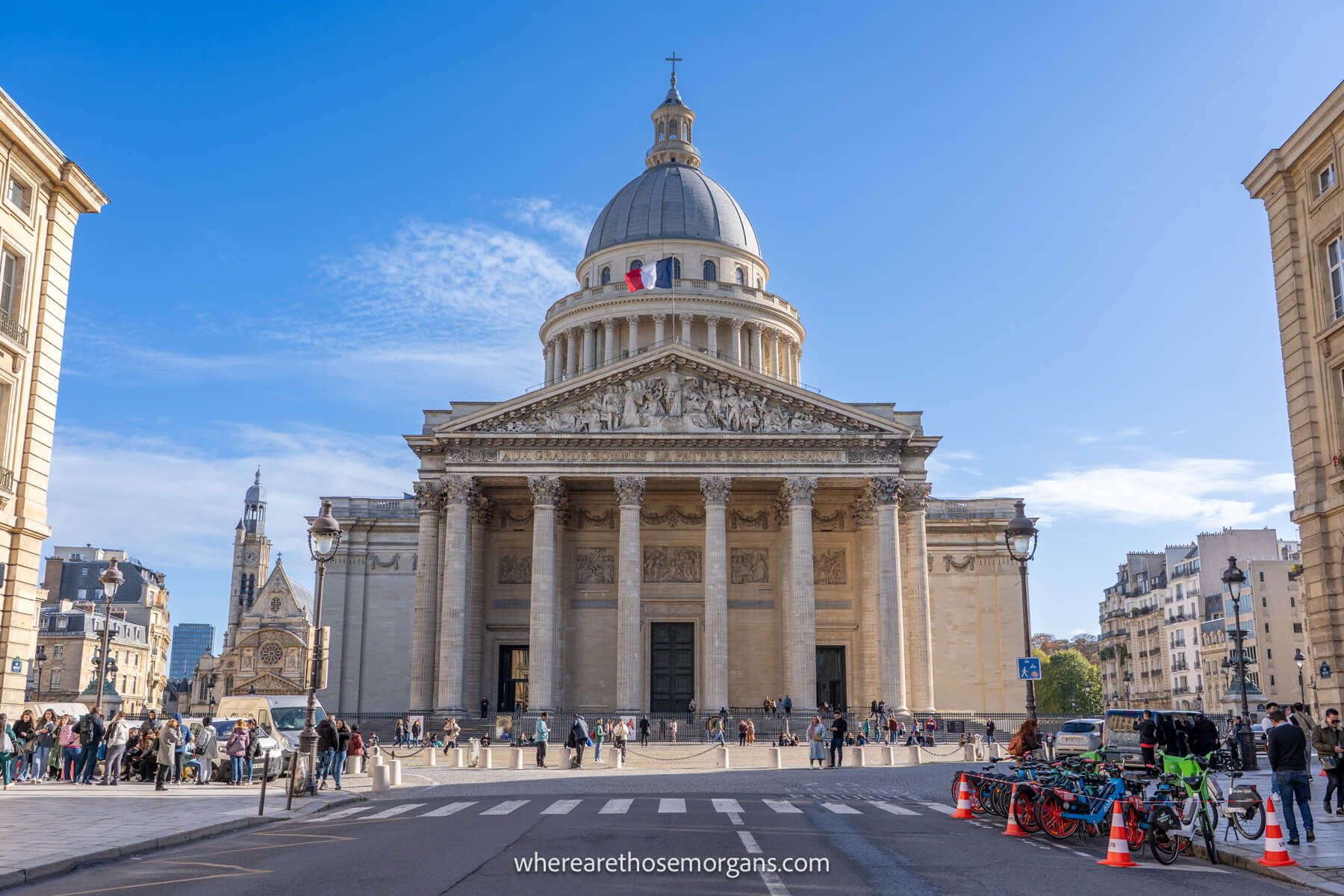 Photo of the outside of the Pantheon in Paris taken from a road approaching the building against a blue sky backdrop