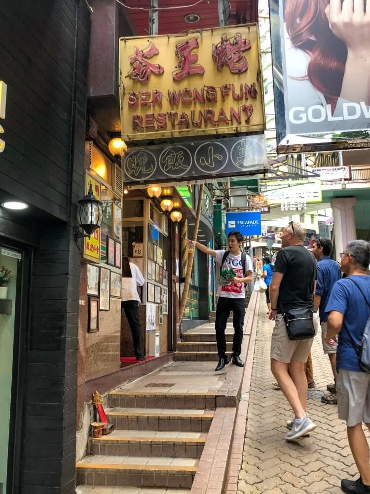 a guide pointing to a sign as something to do in Hong Kong