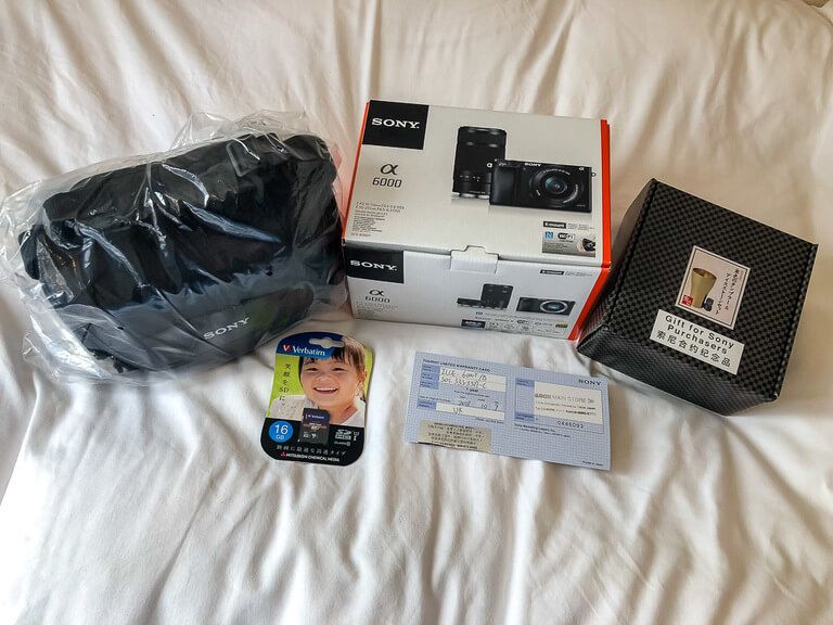 New camera with bag SIM card and warrantee on bed in tokyo