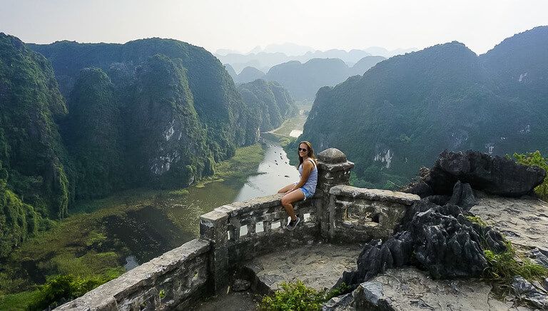 Kristen sat on wall with Tam Coc river in background