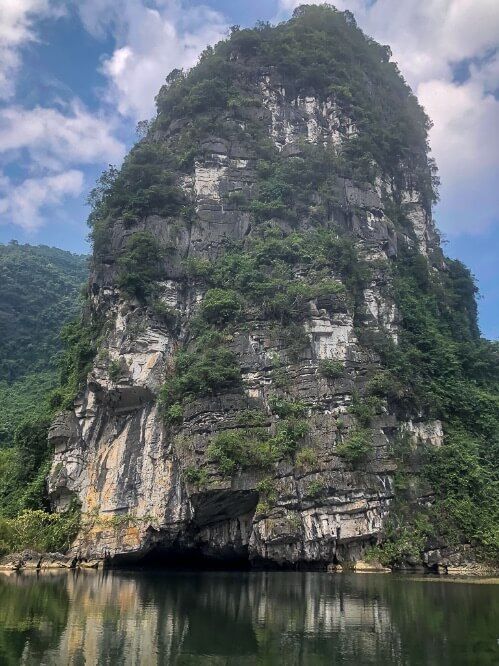 Close up of huge limestone rock with cave entrance Trang An boat tour Tam Coc