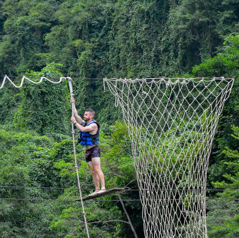 Man navigating the over water obstacle course at Dark Cave