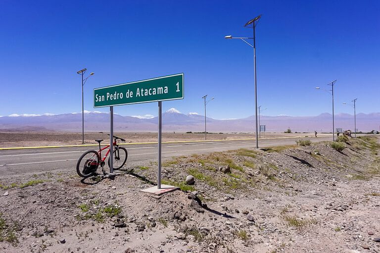 san pedro de atacama 1 kilometer sign with our bike propped up