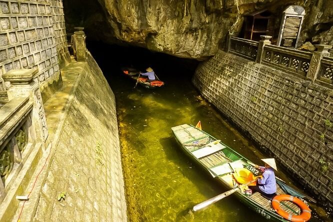 Boats heading down a waterway into a tunnel cave