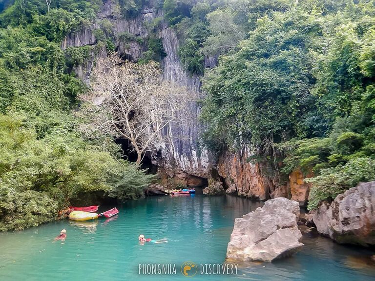 Tourists swimming up to the Dark Cave entrance in turquoise water