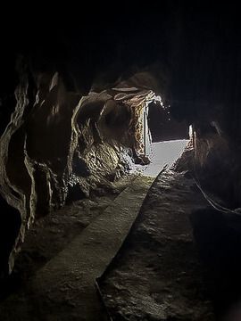 path leading out of tiny entrance to cave light at end of tunnel
