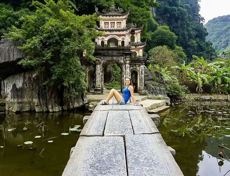 Kristen sat on narrow stone path leading to pagoda entrance Ninh Binh