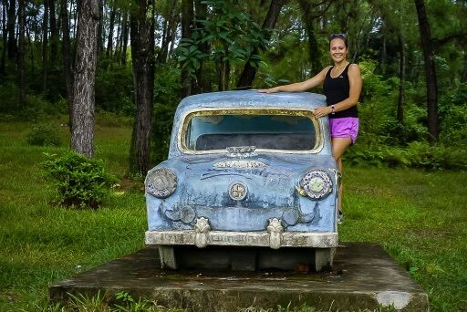 Kristen stood on side of little blue stone car