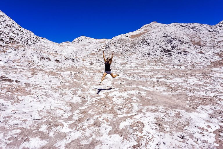kristen leaping into the air above salty rocks in valley of the moon Atacama Desert