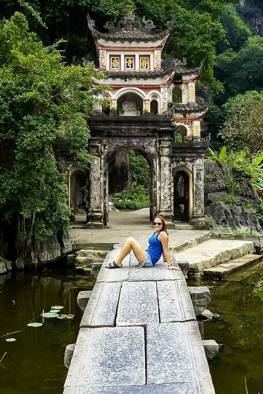 Kristen sitting on bridge in front of Bich Dong pagoda entrance Tam Coc