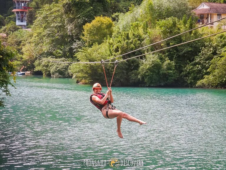 Woman zip lining 400m over the water in Phong Nha