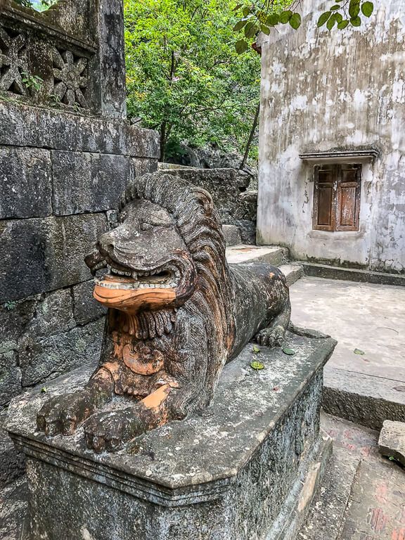 Stone statue of a lion in prone position gardens of Bich Dong