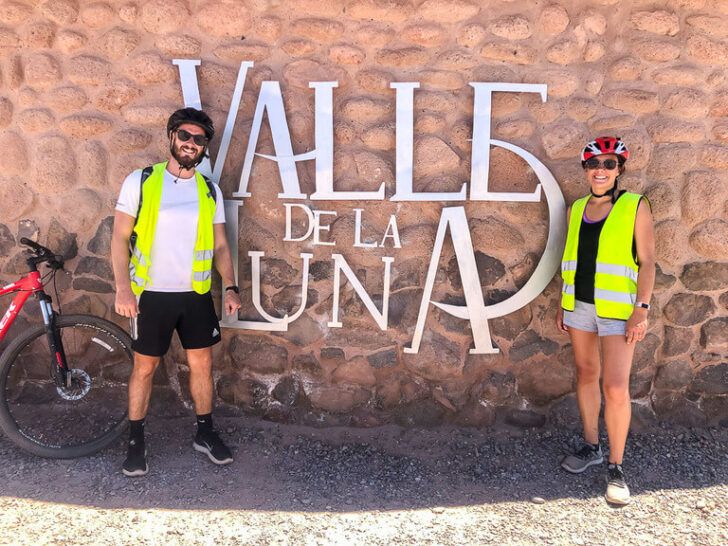mark and kristen with mountain bike in front of valle de la luna entrance sign