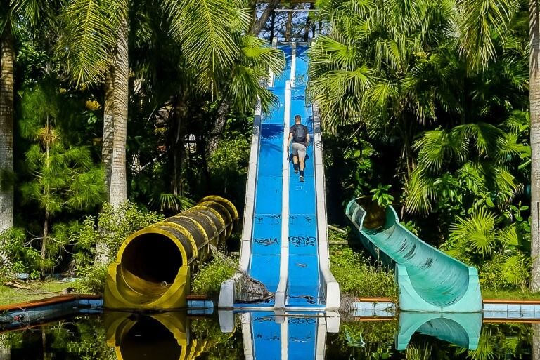 Mark walking up an abandoned blue water slide into trees