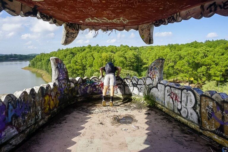 Mark looking at the drop out of a dragons mouth in hue abandoned water park