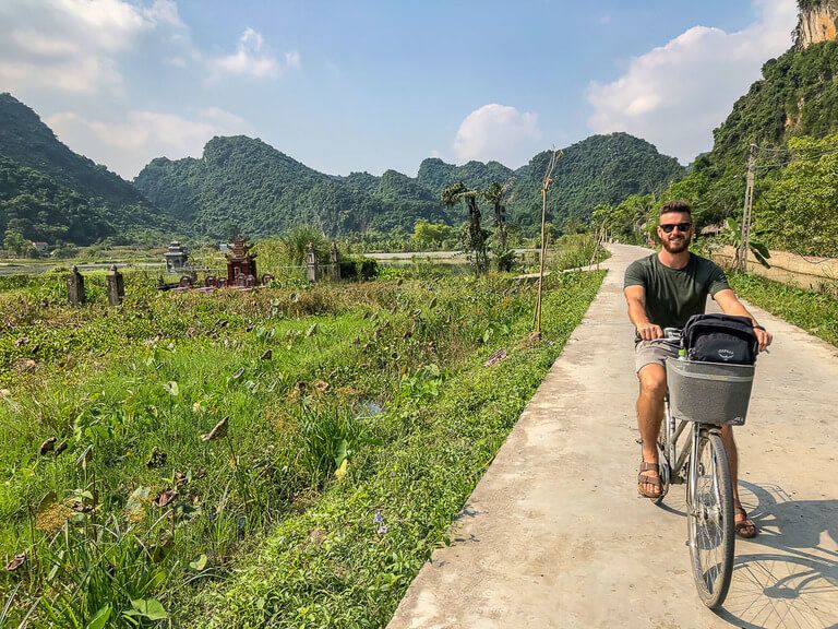 Man on a bike in a field surrounded by limestone karsts