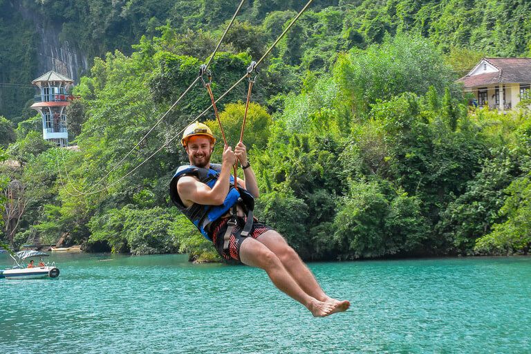 one of best things to do in Phong Nha zip lining over turquoise water to dark cave