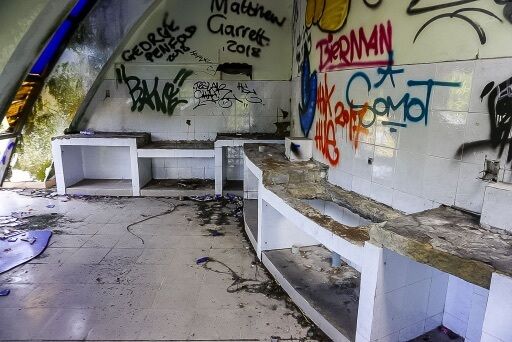rundown room wit graffiti and smashed glass in hue
