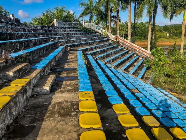 blue and yellow seats amphitheater in abandoned water park hue overgrown with vegetation