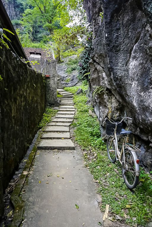 Narrow path with Bich Dong grounds wall to left and bicycle parked