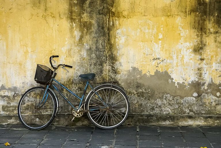 Blue bike leaning up against ancient yellow wall