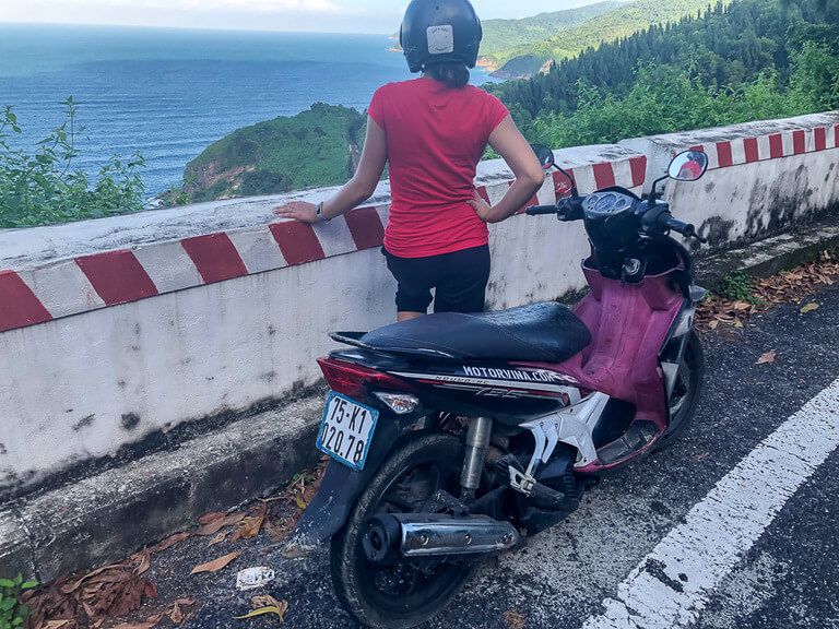 Kristen with motorbike and helmet on looking to sea on hai van pass vietnam