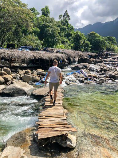 Mark walking over a wooden bridge over a river