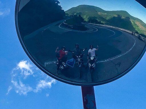 Mark Kristen and Phu motorbikes in mirror showing hairpin bend on hai van pass