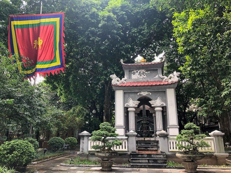 Small white temple and flag flying surrounded by trees