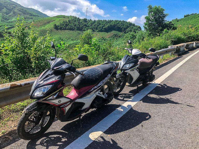 Mark and Kristens pink and white motorbikes on side of road crossing hai van pass Vietnam