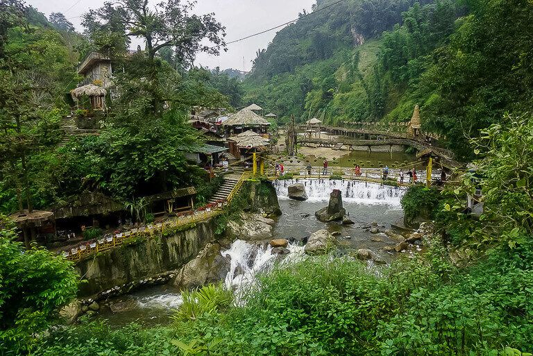 Cat cat village on sapa itinerary with green vegetation, waterfalls and wooden structures