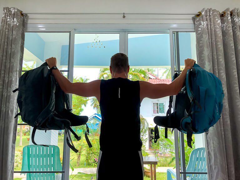 Mark doing shoulder raises with backpacks improvised workouts when traveling