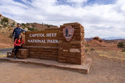 Mark and kristen leaning against Capitol Reef entrance sign Utah