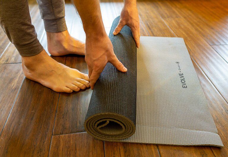 Mark unrolling a yoga mat on hard wood floor perfect traveling workouts