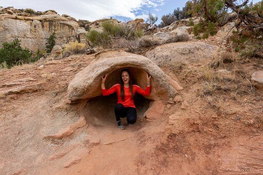Kristen crouched inside rock crevice Hickman bridge hike