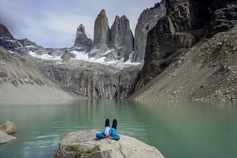 Kristen laying on a boulder in front of Torres del Paine laguna enjoying the hike