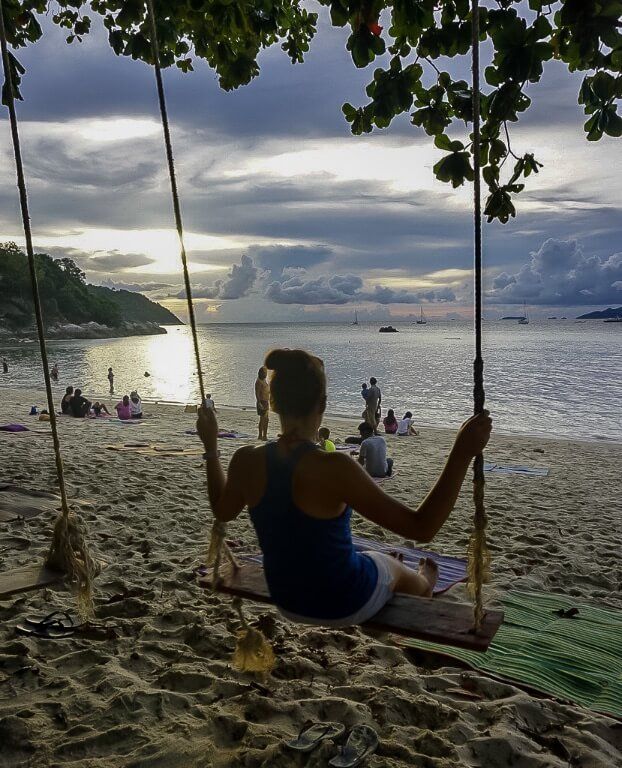 Kristen on a wooden rope swing at Sunset beach Koh Lipe with awesome clouds illuminated