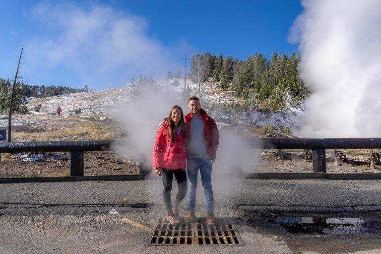 Mark and Kristen standing over a vent with hot steam rising at Yellowstone National park 4 days itinerary