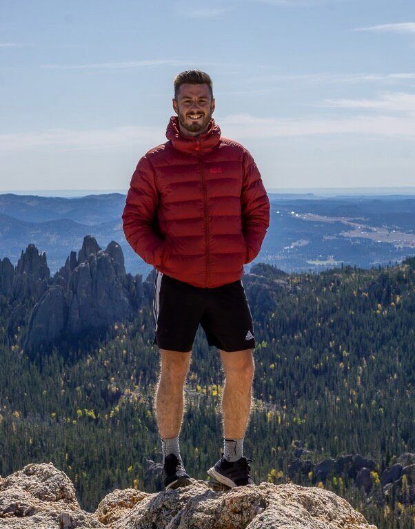 Mark at summit of Black Elk Peak hike wearing thick grey hiking socks tips for beginners
