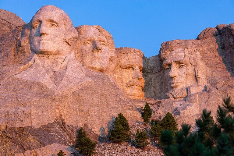 Mount Rushmore illuminated by pink sunlight at sunrise Black Hills National Forest South Dakota