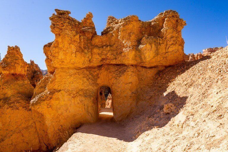 Arched doorway built into orange rock on hiking trail in Utah