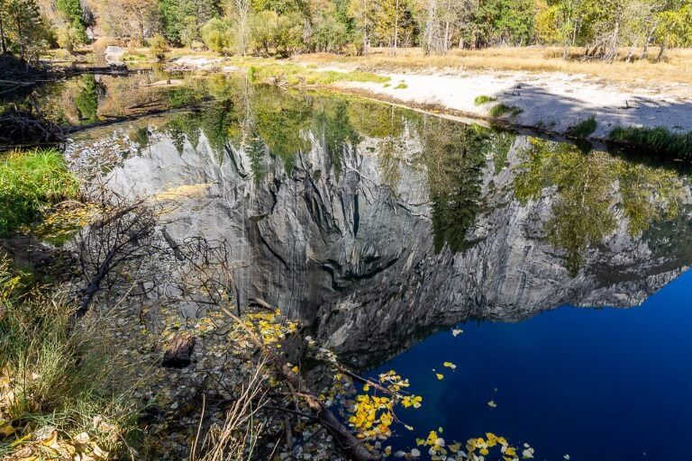 perfect reflection in still Merced river water granite rock