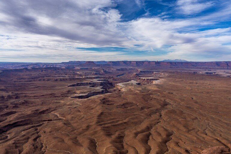 View over a rugged landscape with carved out valleys and a blue sky