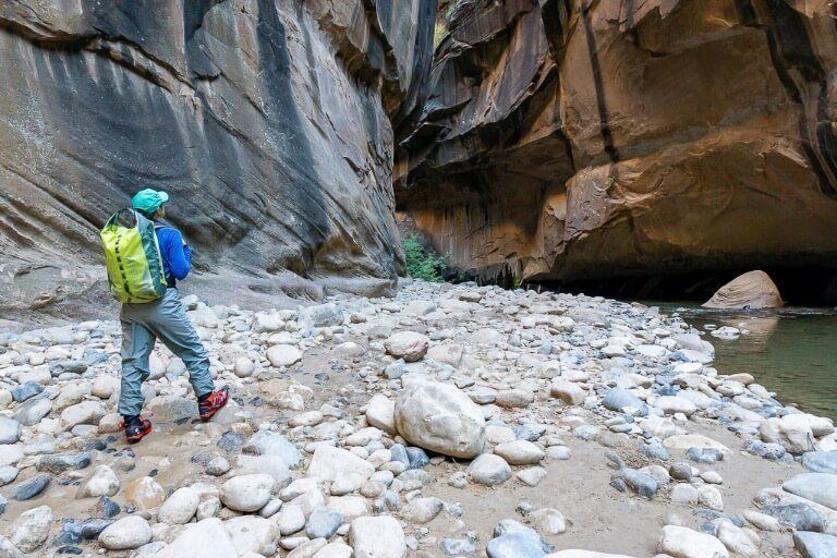 Kristen standing on rocky path next to river in slot canyon the Narrows hiking trail Zion national park