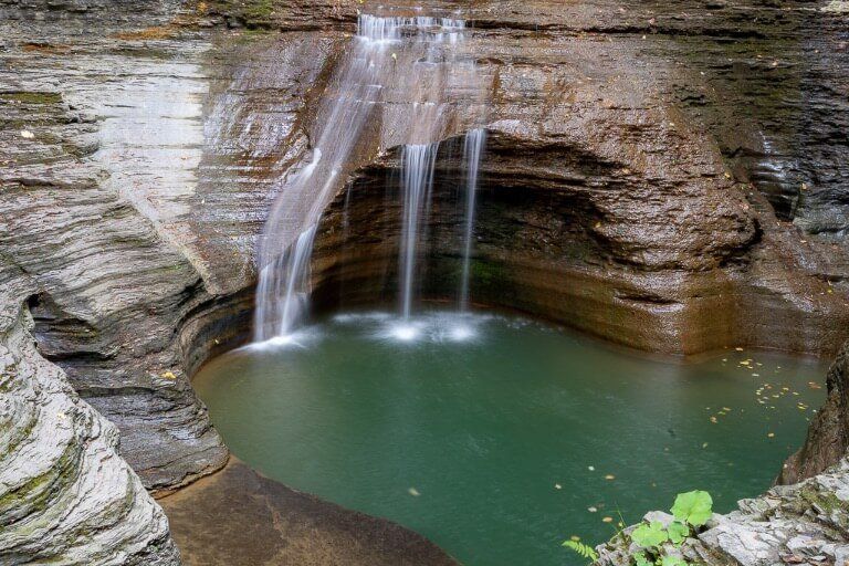 Waterfall running almost dry in state park near Ithaca ny finger lakes into a green plunge pool