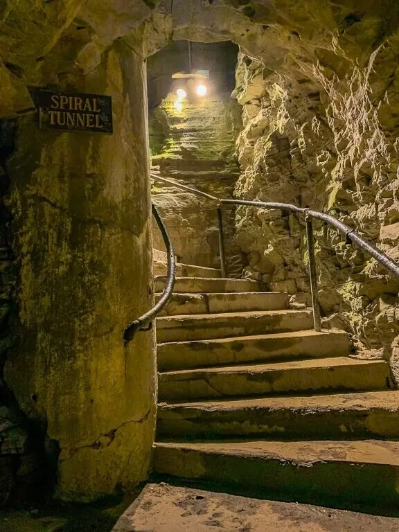  Escalier en pierre en colimaçon éclairé par des lumières vives 