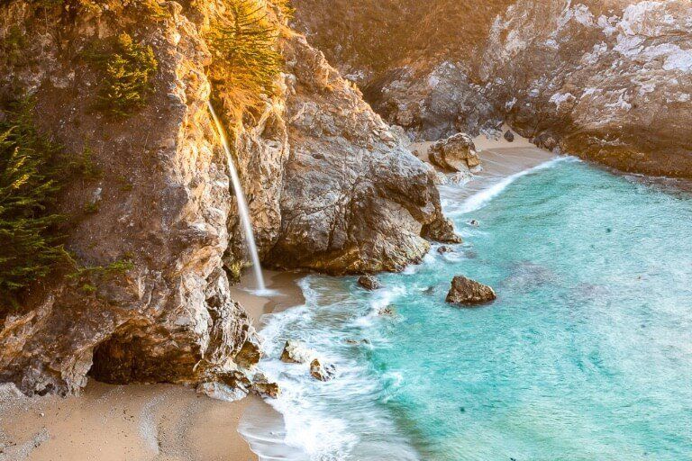 McWay falls is the single most stunning natural feature along California Pacific coast highway 1 thin waterfall plunging onto a sandy beach and joining the ocean as the tide gently washes in