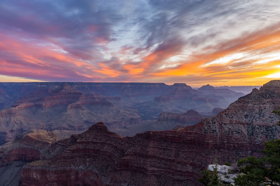 Incredibly beautiful sunrise at mather point grand canyon south rim streaking colors in clouds with canyon glowing purple at dawn